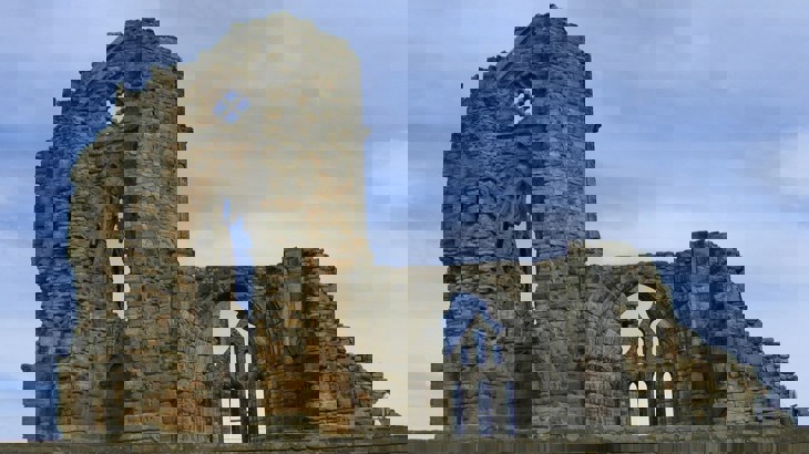 Wall of ruined Gothic abbey against blue sky