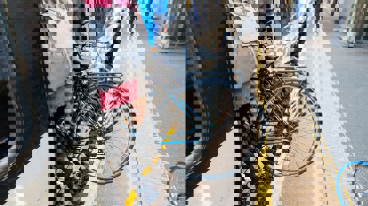 Bike being carried by person with blue backpack from train platform onto train