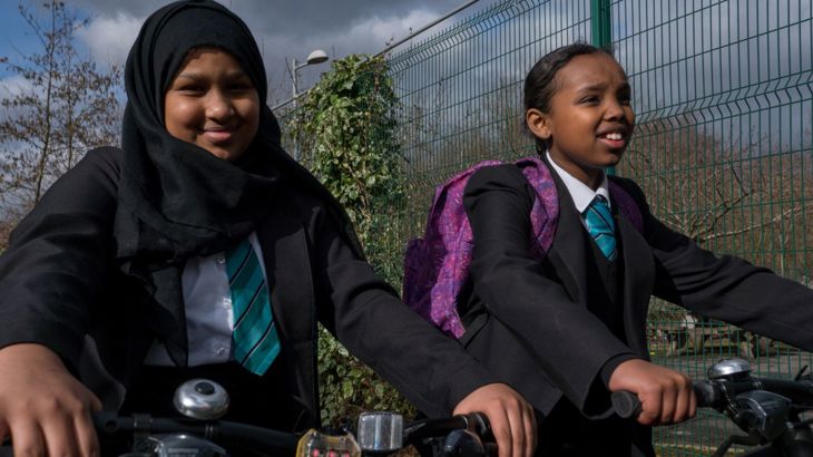 Two secondary school children riding bikes.