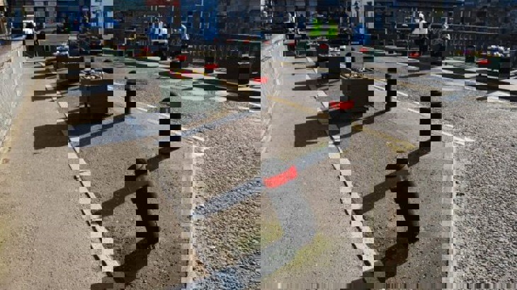 Black bollards with red stripes on pavement by road