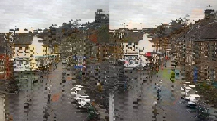 Town centre in Scottish town with Christmas tree, walkers and two parked cars