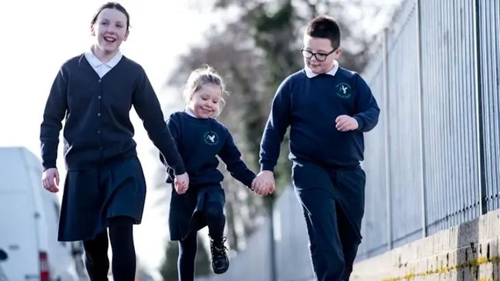 Children in school uniform walking to school holding hands