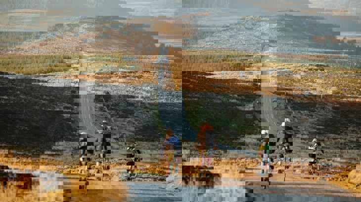 Three cyclists on road through Scottish countryside