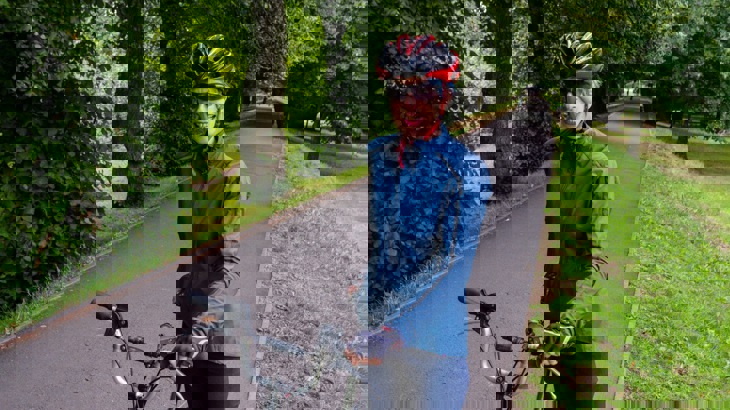 A female poses with her bike in a park