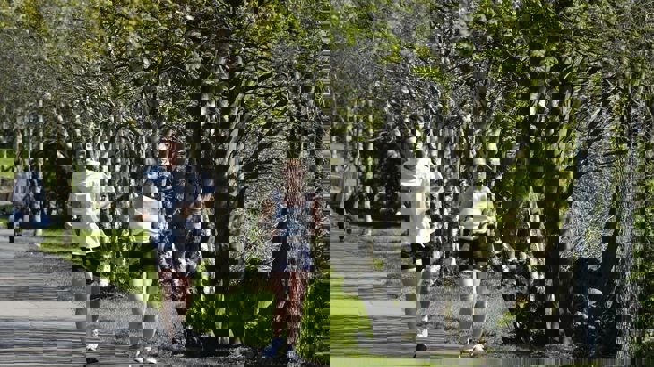 Two people running along tree-lined path