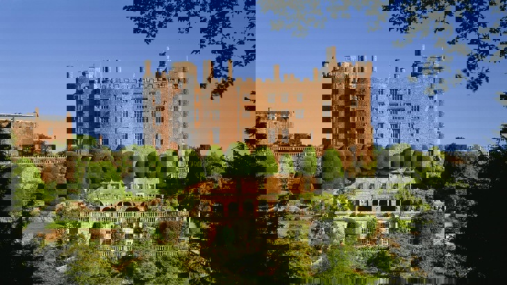 Red brick castle-style mansion in front of formal gardens