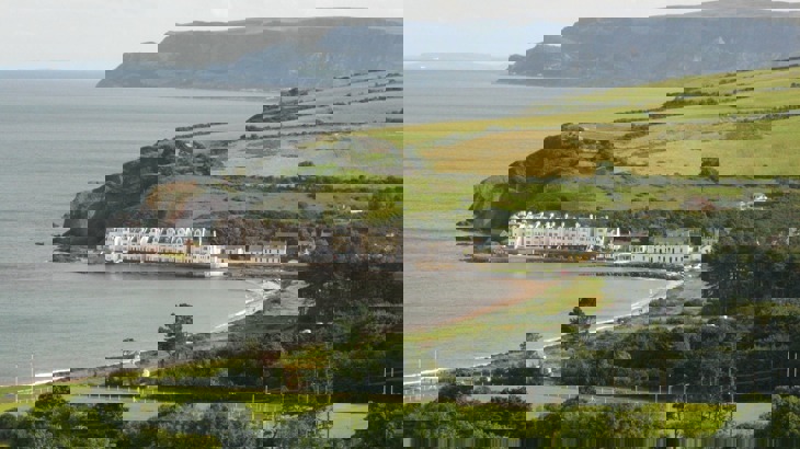 View of coastal village with row of white buildings, plus fields and trees