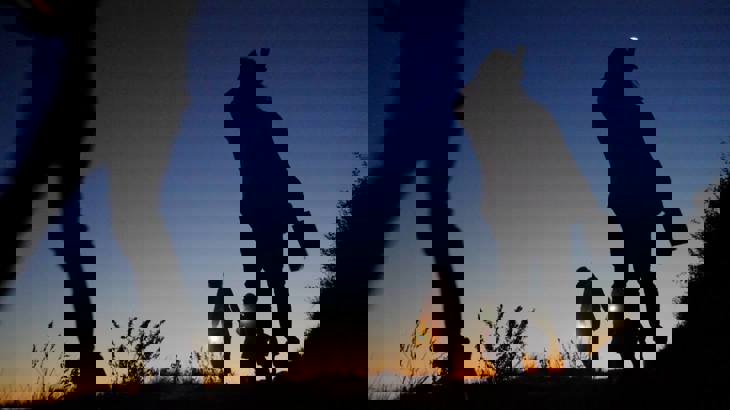 Silhouettes of people against the sky with torches at dusk