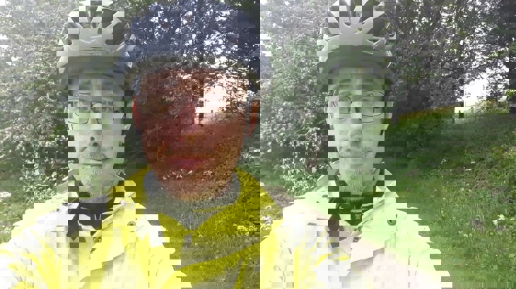 Man wearing glasses, black cycling helmet and high-vis jacket