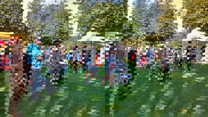 Families milling about in park with tents and bouncy castle