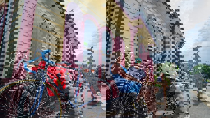 Two people sat at table on table outside old fashioned train station waiting room with bikes in the foreground