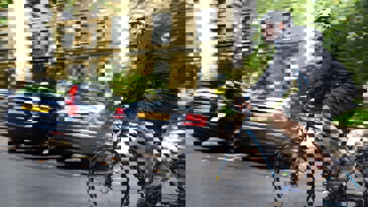 A man rides an e-bike up a hill in a residential area