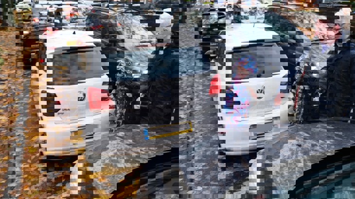 A parent walks a child inbetween cars outside of a school 