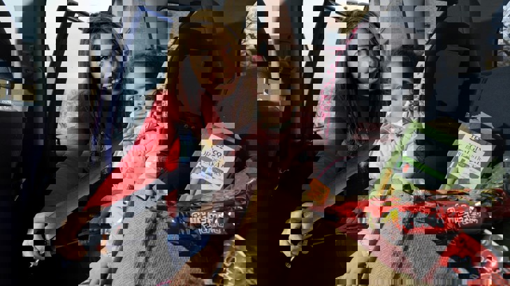 A mum fastens her daughter's seat belt in the car after going shopping