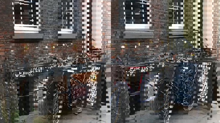 Two bikes on railings outside basement cafe on urban street