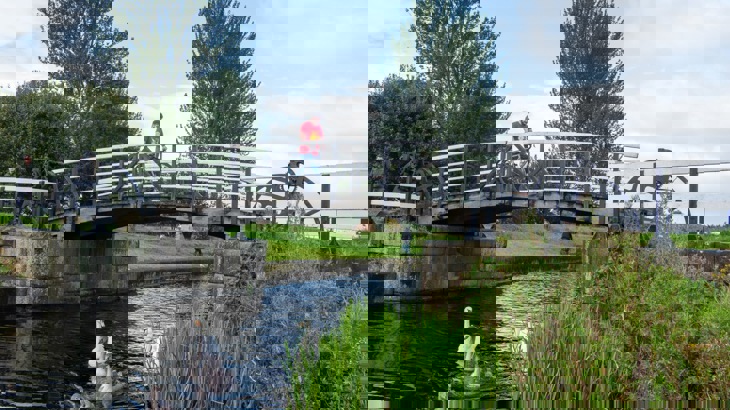 Man Crossing A Bridge Over A Canal 