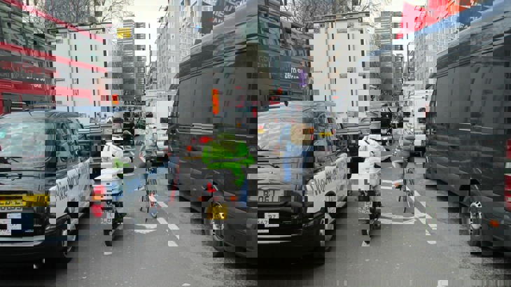 A person on a bicycle tries to navigate through congestion in London