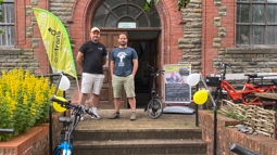 Walk Wheel Cycle Trust and Welcome to Our Woods staff stand outside of the Old Library with a selection of e-bikes.