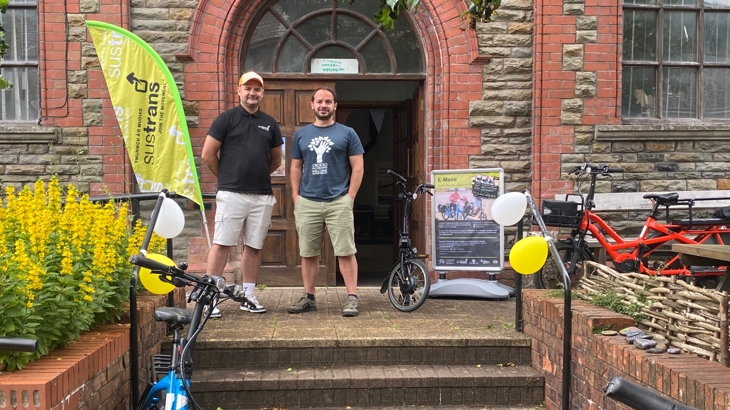 Walk Wheel Cycle Trust and Welcome to Our Woods staff stand outside of the Old Library with a selection of e-bikes.