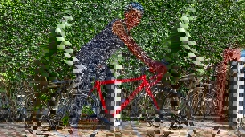 Kirsten, wearing a helmet and stood with her bike smiling at the camera