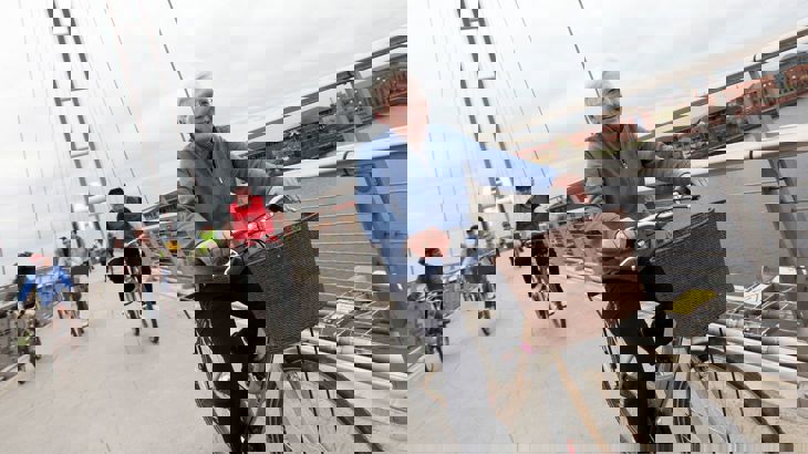 Elderly lady riding her bike over a bridge