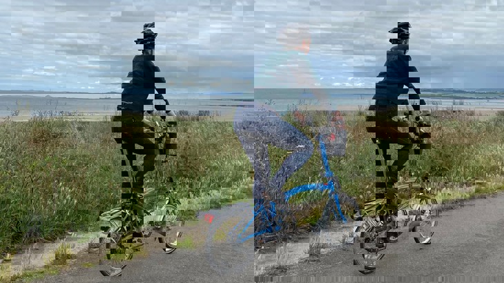 Tierney cycling on her blue e-bike along the coast