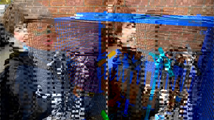 Boy smiling as he locks his scooter up at a stand in the school playground