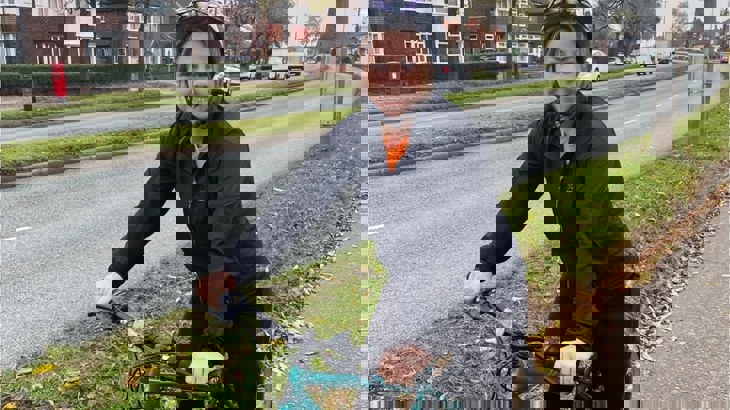 Liverpool Labour Councillor, Sharon Connor, standing with her bike on a residential paved street wearing a helmet and a black waterproof jacket.