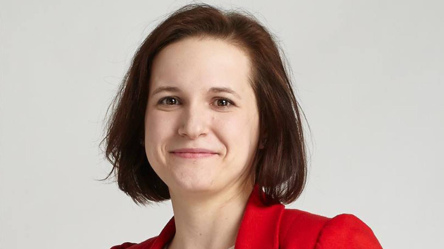 Head shot of Kasia Koziel with short brunette hair, wearing a red blazer and facing the camera