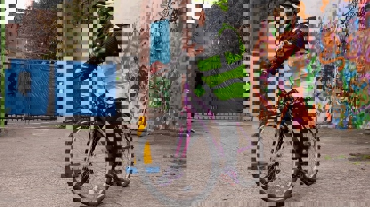 Woman in high vis vest cycles in a car park