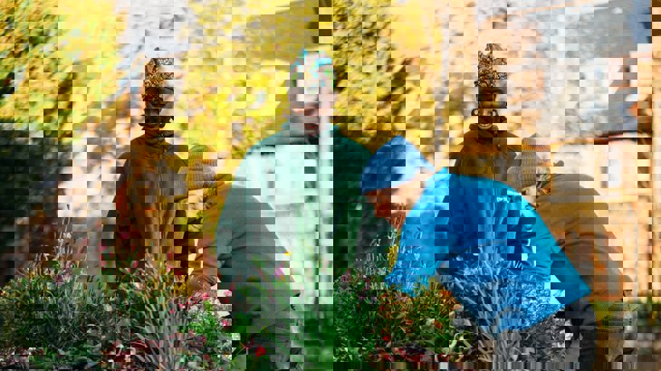 Two women chatting, planting flowers in a street planter on their road.