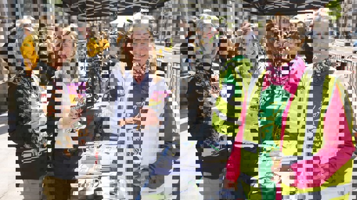 staff member dianne at an information stand with two women holding cycling literature at cycle to work day event outside in Belfast City Centre