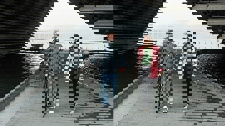 Man holding a bike walking with a woman in Dundee, with the V&A building in the background