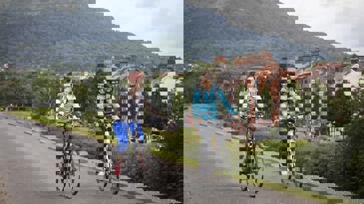 two women cycling along a traffic free path in the Water Works park, North Belfast with Cavehill mountain in the background