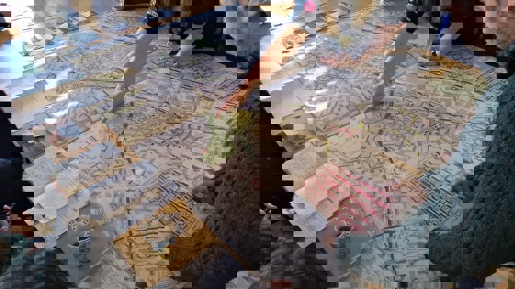 People looking at and point to a big map on a table