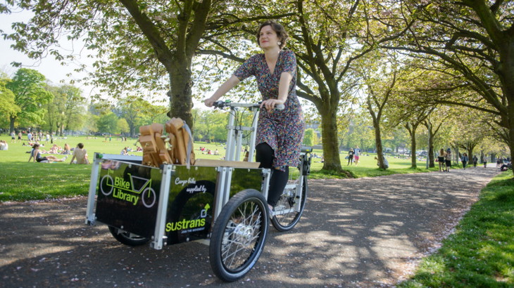 Outside in the park cycling an electric delivery cargo bike, ecargo bike, ebike.