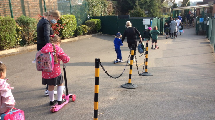 children lining up for school with scooters and bikes
