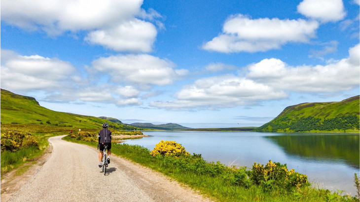 Person cycling along a traffic-free route next to a lake