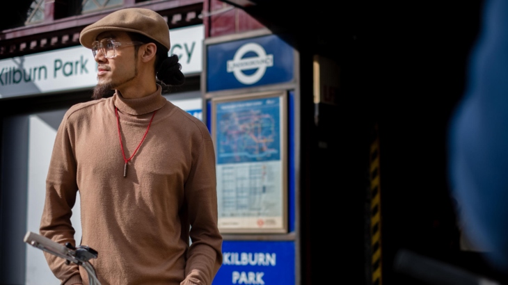 Person beside bike, stood outside Kilburn Park station in London.