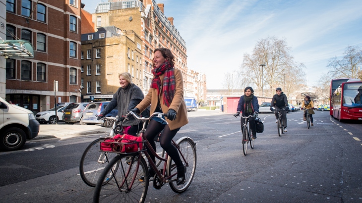 People in gloves and scarves cycling in London during winter 