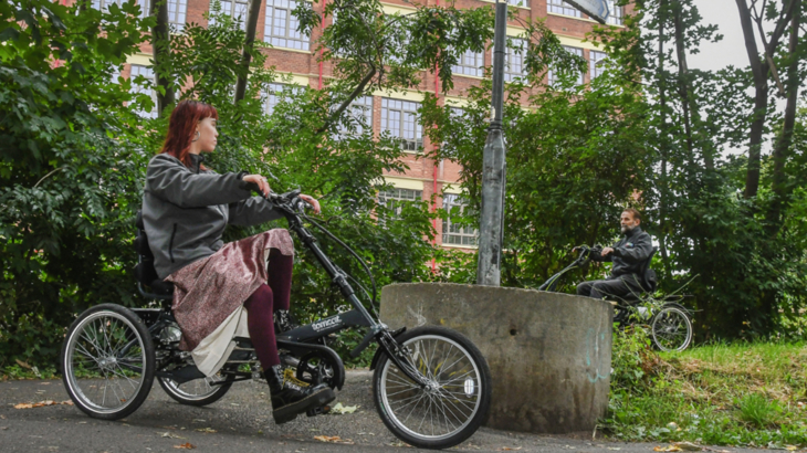 Two people riding trikes on the Foss Islands Path in York on an overcast day
