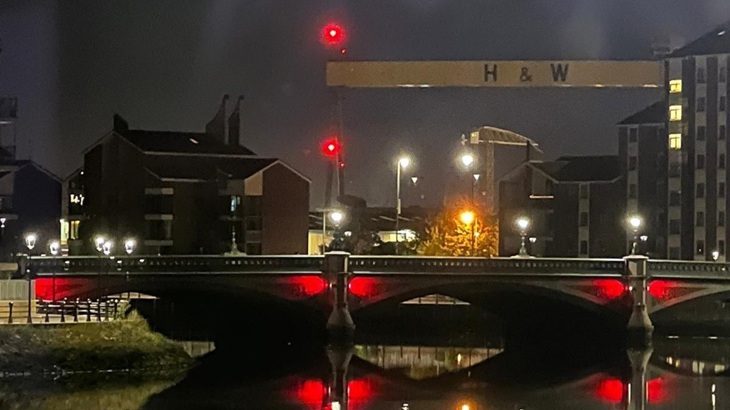 Red lighting under the Albert Bridge in Belfast to help starlings roost. H&W crane of shipyard in background.