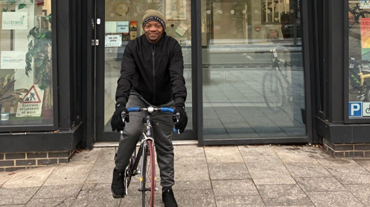 A man stood with his bike wearing a hat and gloves outside one of our cycling and walking hubs in the north of England