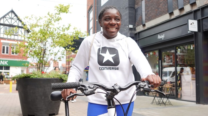 Phoebe, an interviewee for the Cycling Opportunity report, stands with her bike in Sale town centre, Manchester.