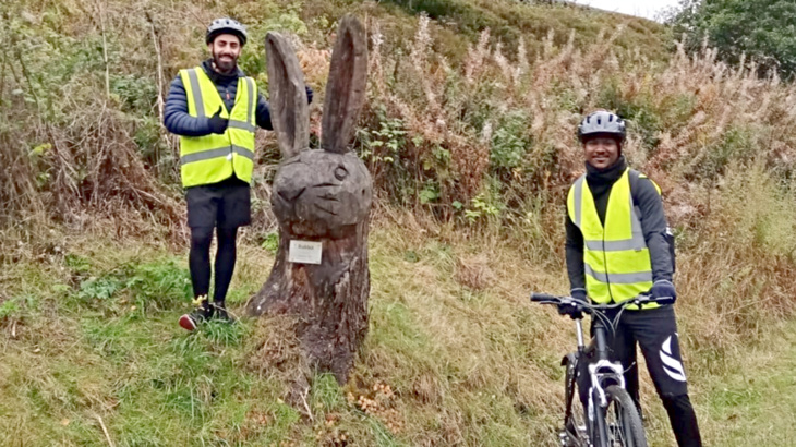 Two men wearing high-vis vests and helmets stood with their bikes smiling on a section of the Network